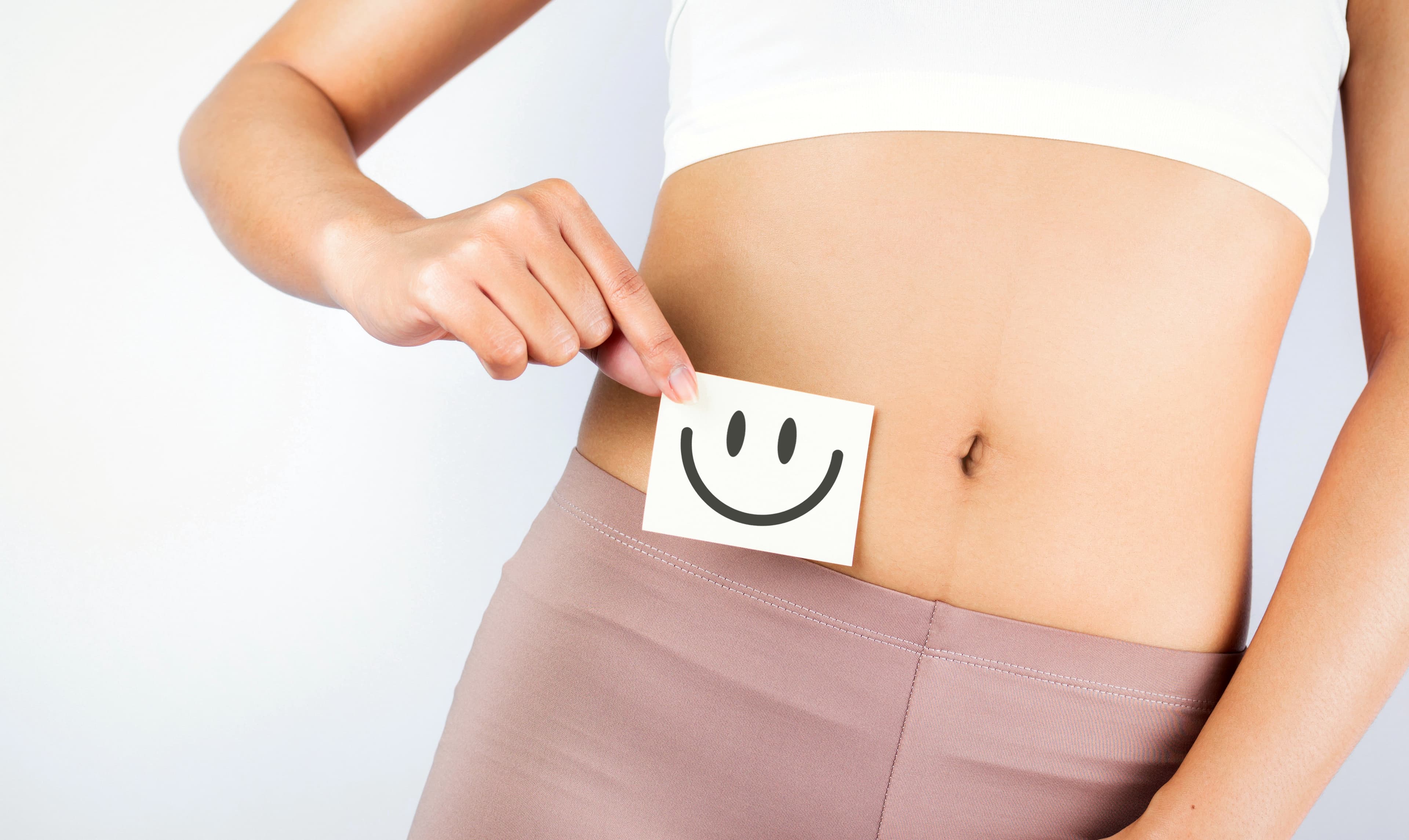 A female holding a smiley face in front of her gut